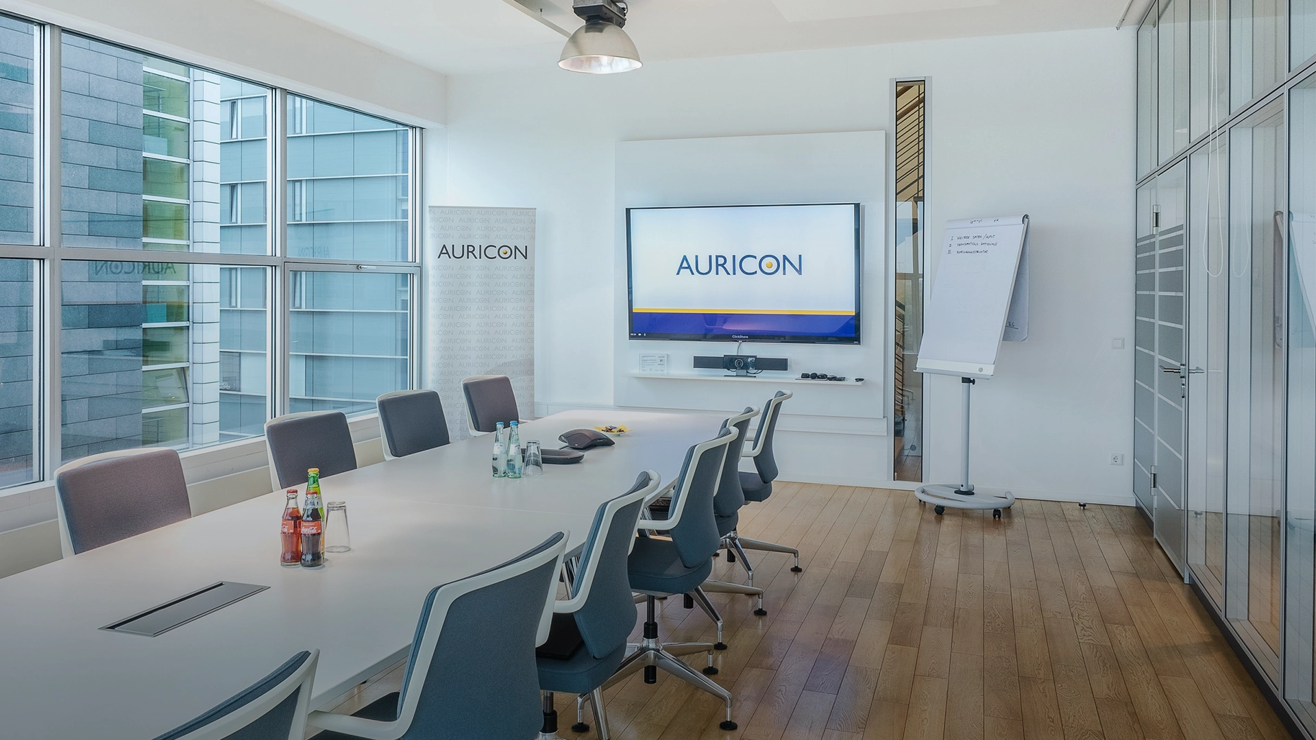 Moderner Konferenzraum bei AURICON mit großem Besprechungstisch, Bildschirm und Flipchart